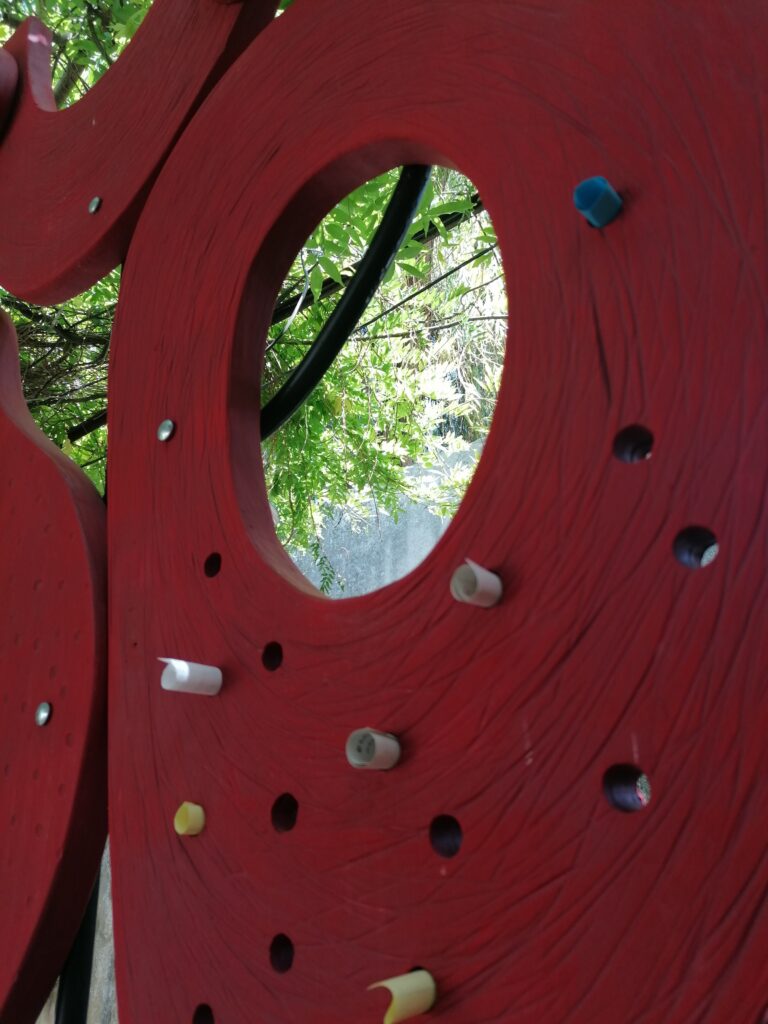 A close view of a red Baci Sospesi form with small openings holding paper messages.
