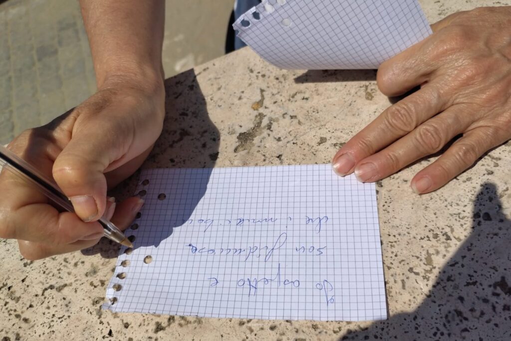 Hands writing a message on paper at a Baci Sospesi installation.