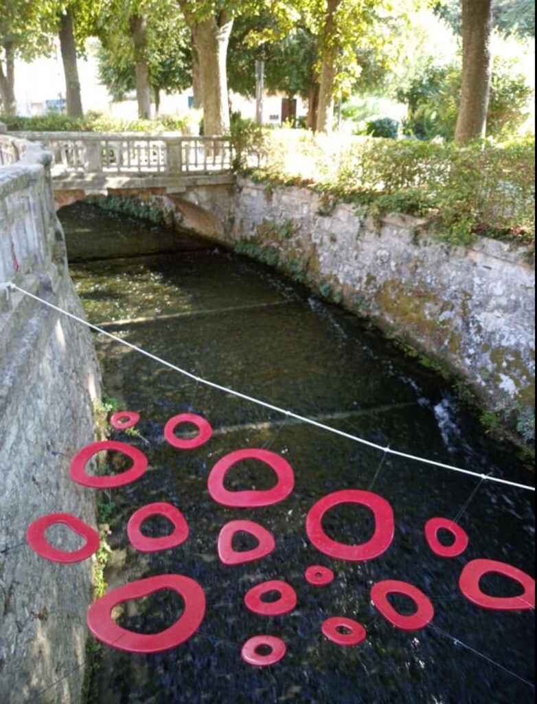 Red Baci Sospesi forms suspended above the river in Pioraco.